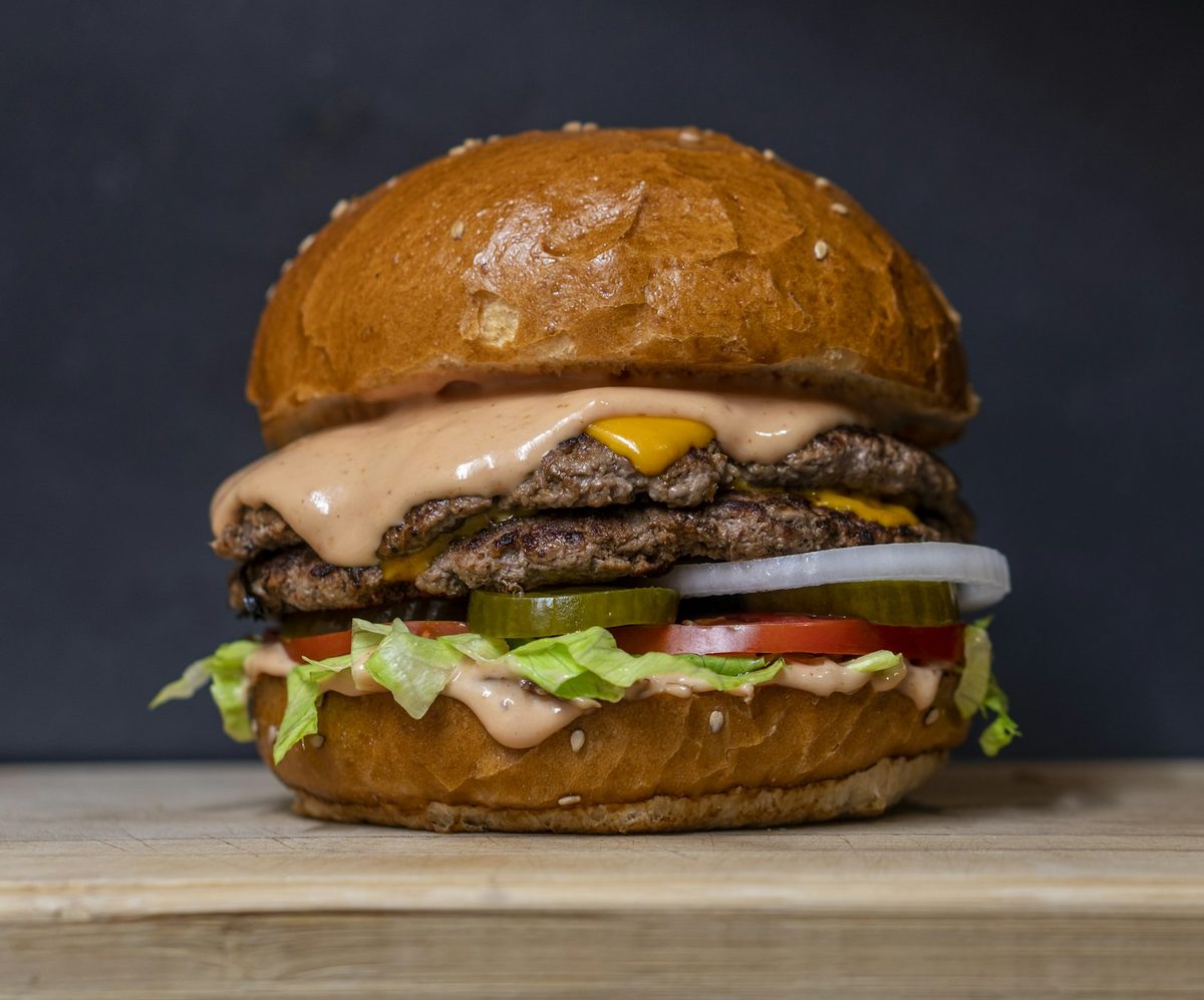 Hamburguesa doble con queso fundido, lechuga, tomate, cebolla y pepinillos