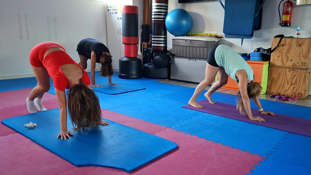 Tres alumnas estirando la espalda en postura de perro boca abajo al final de la clase de pilates